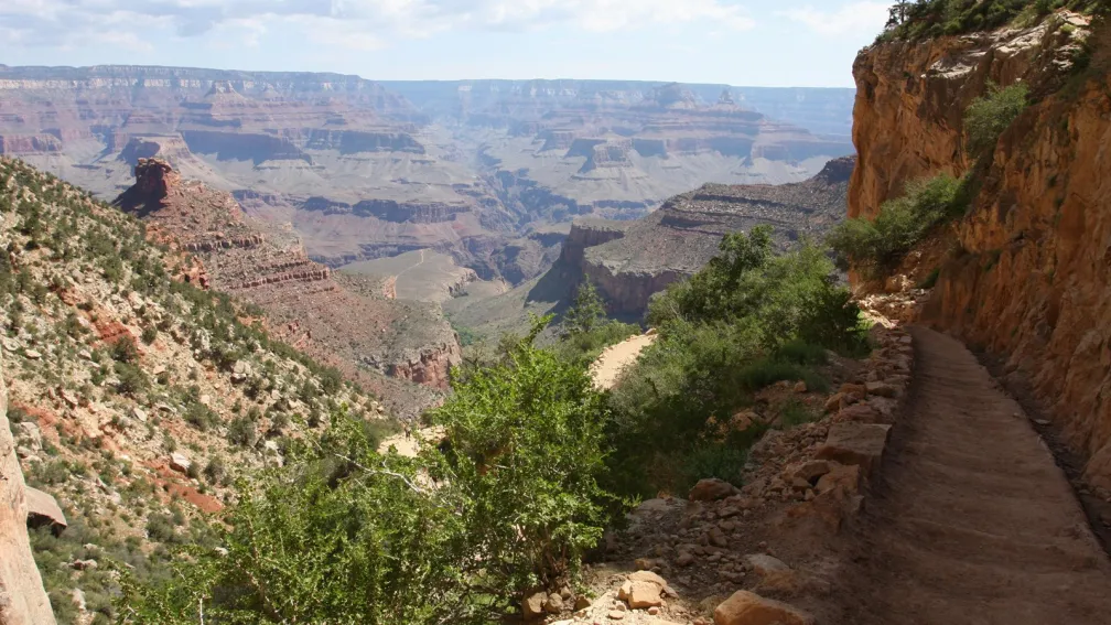 Photo of Bright Angel Trail, with a low stone wall on one size and a cliff face on the other.