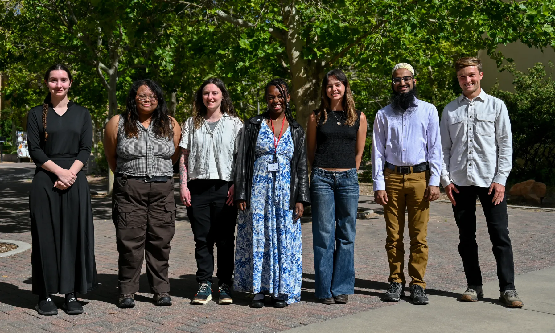 Five interns in outdoor wear stand near a geology road outcrop.