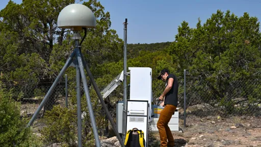 man lifts battery into GPS station enclosure