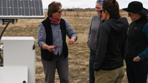 4 people talking in front of opened enclosure box with solar panels