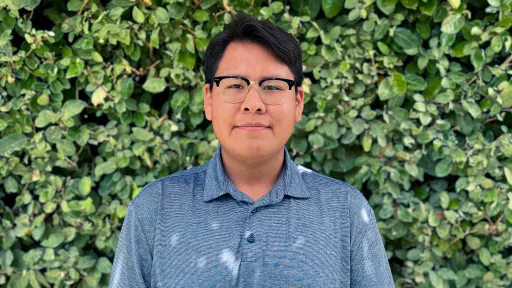 RESESS intern Elishua smilling for a headshot with green foliage in the background.