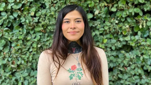 GLP intern Kaissa smiling for a headshot with green foliage in the background.