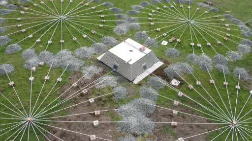 photo of infrasound array on the ground, box in center and four connected circular arrays of radial cables