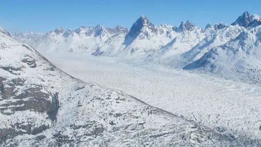 Photo looking up a glacier filling a valley, with snow-covered peaks on either side.