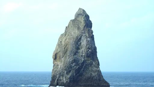 Photo of a tall, steep rock island jutting out of the sea.