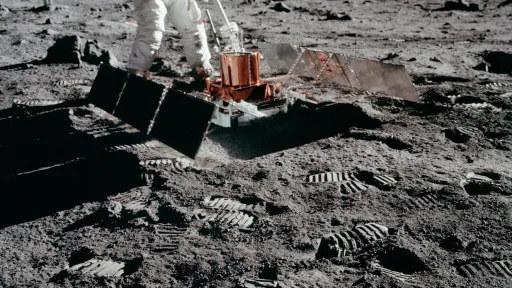 Photo of an astronaut deploying a sled-sized instrument with solar panels on either side.