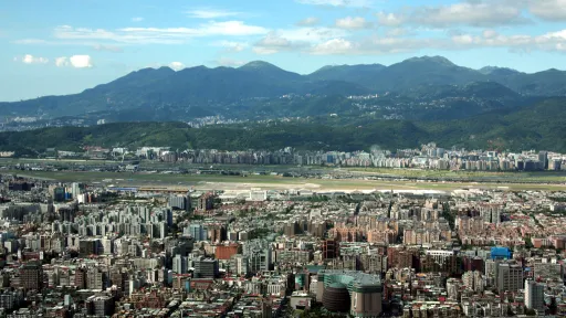 Photo overlooking a city full of multi-story buildings, with a row of lumpy peaks behind.