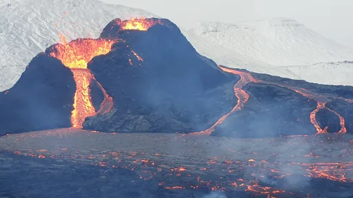 Photo of a river of lava pouring from a small cone.