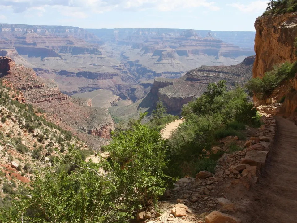 Photo of Bright Angel Trail, with a low stone wall on one size and a cliff face on the other.