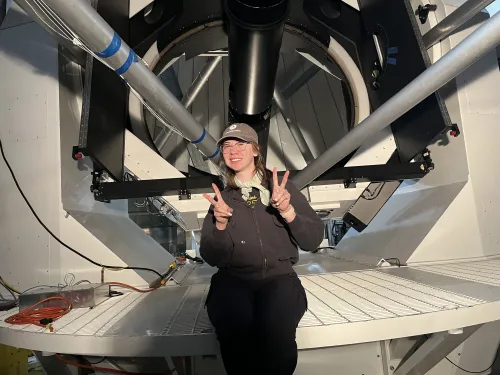 Leah April smiling in front of a telescope at the Magdalena Ridge Observatory in New Mexico. 