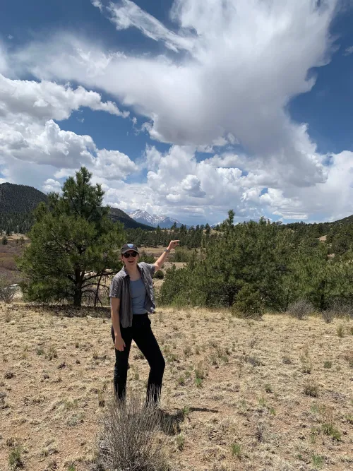 Alaina Foster posing in front of trees and mountains. 