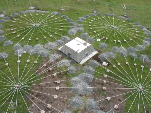 photo of infrasound array on the ground, box in center and four connected circular arrays of radial cables