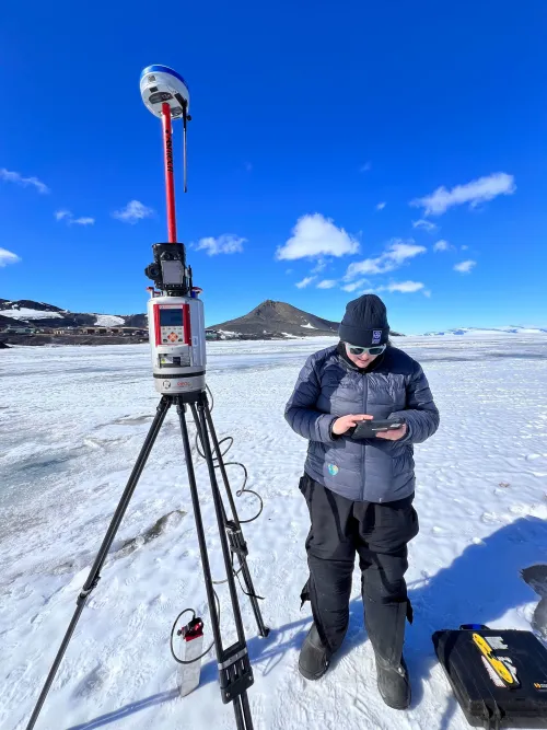 A person next to a terrestrial laser scanner on a tripod uses a tablet computer.