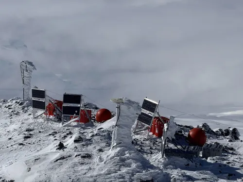 Rime-coated instruments on a snowy ridge, including red cases and solar panels.