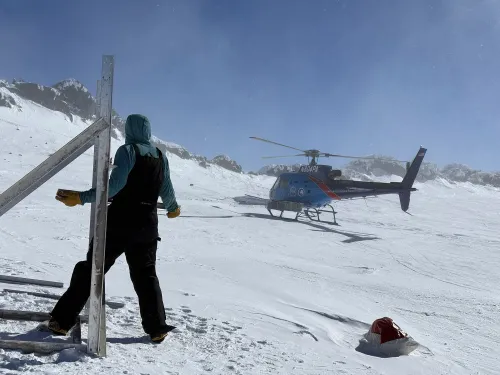 Person assembling solar panel set looks at a landing helicopter nearby.