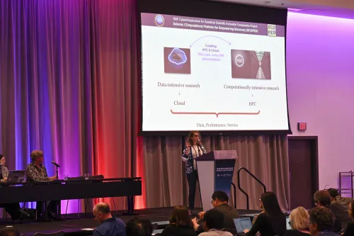 A speaker at a lectern with slides on the projector screen behind them.
