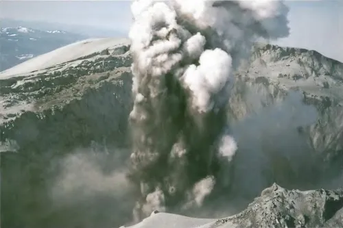 Looking into the summit crater of Mount St. Helens, a thick column of steam and ash spouts out. 